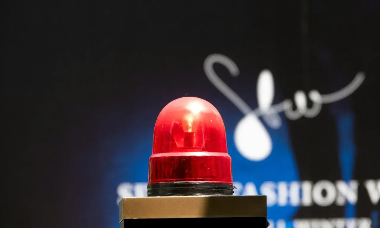Une sirène rouge clignote, comme son alarme maison, sur un fond sombre avec un logo blanc stylisé.