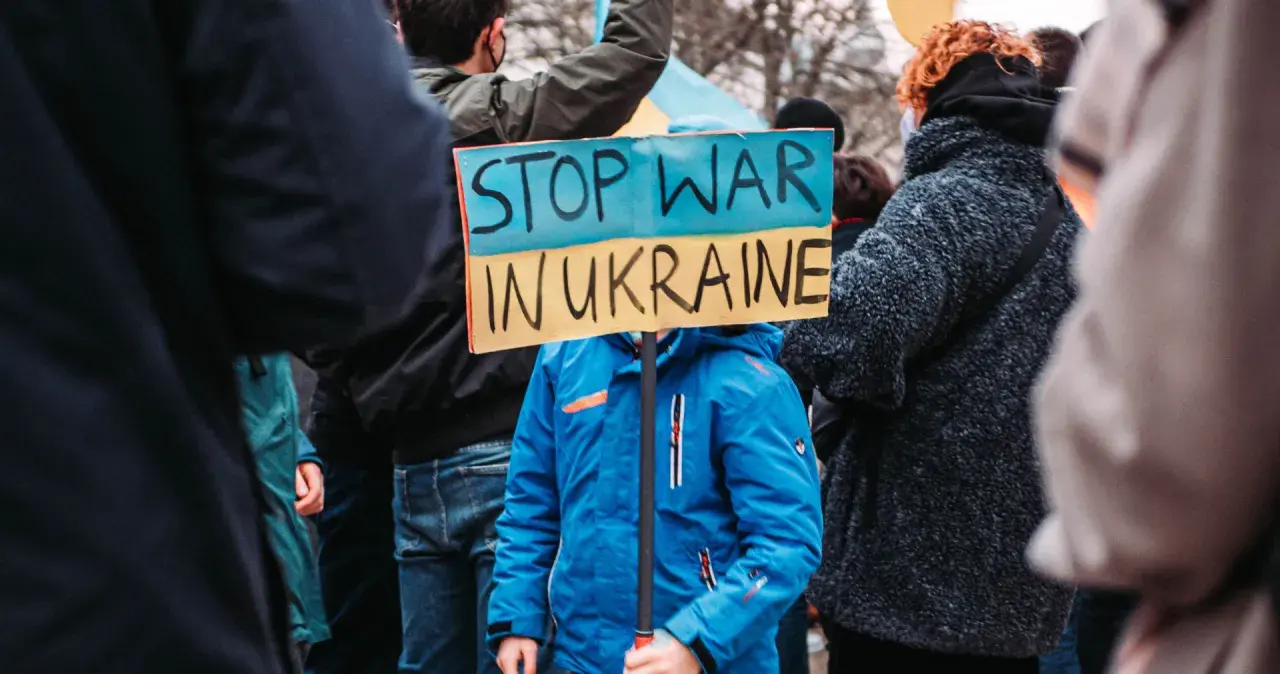 Kind hält Schild "Stop War in Ukraine". Ein starkes Bild, das an die Stimmen im Ukraine Podcast erinnert, die Frieden fordern.