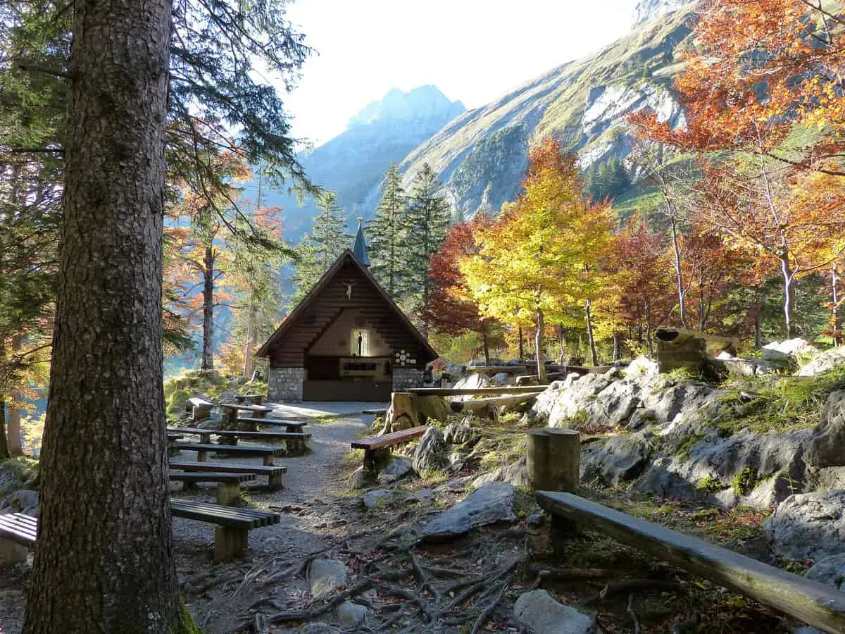Holzhütte mit Bänken und bunten Bäumen im Herbst. Perfekt für eine Seealpsee Wanderung.