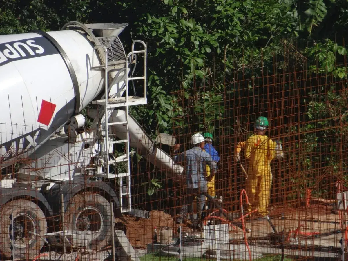 Betoniarka dostarcza beton na budowę. Zastanawiasz się, ile kosztuje metr betonu z betoniarki? Pracownicy w kaskach nadzorują rozładunek.