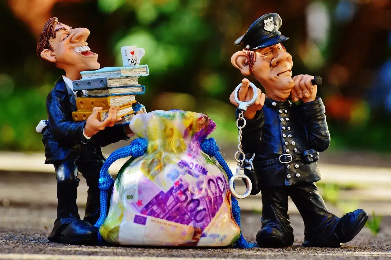 Figurki policjanta z kajdankami i mężczyzny z książkami i torbą pieniędzy.