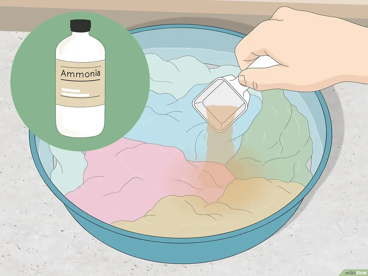 Eine Hand gibt eine Messlöffel-Menge einer Flüssigkeit in eine Schüssel mit bunten Kleidungsstücken und Wasser. Die Flüssigkeit hilft, den **Geruch aus Kleidung entfernen**.