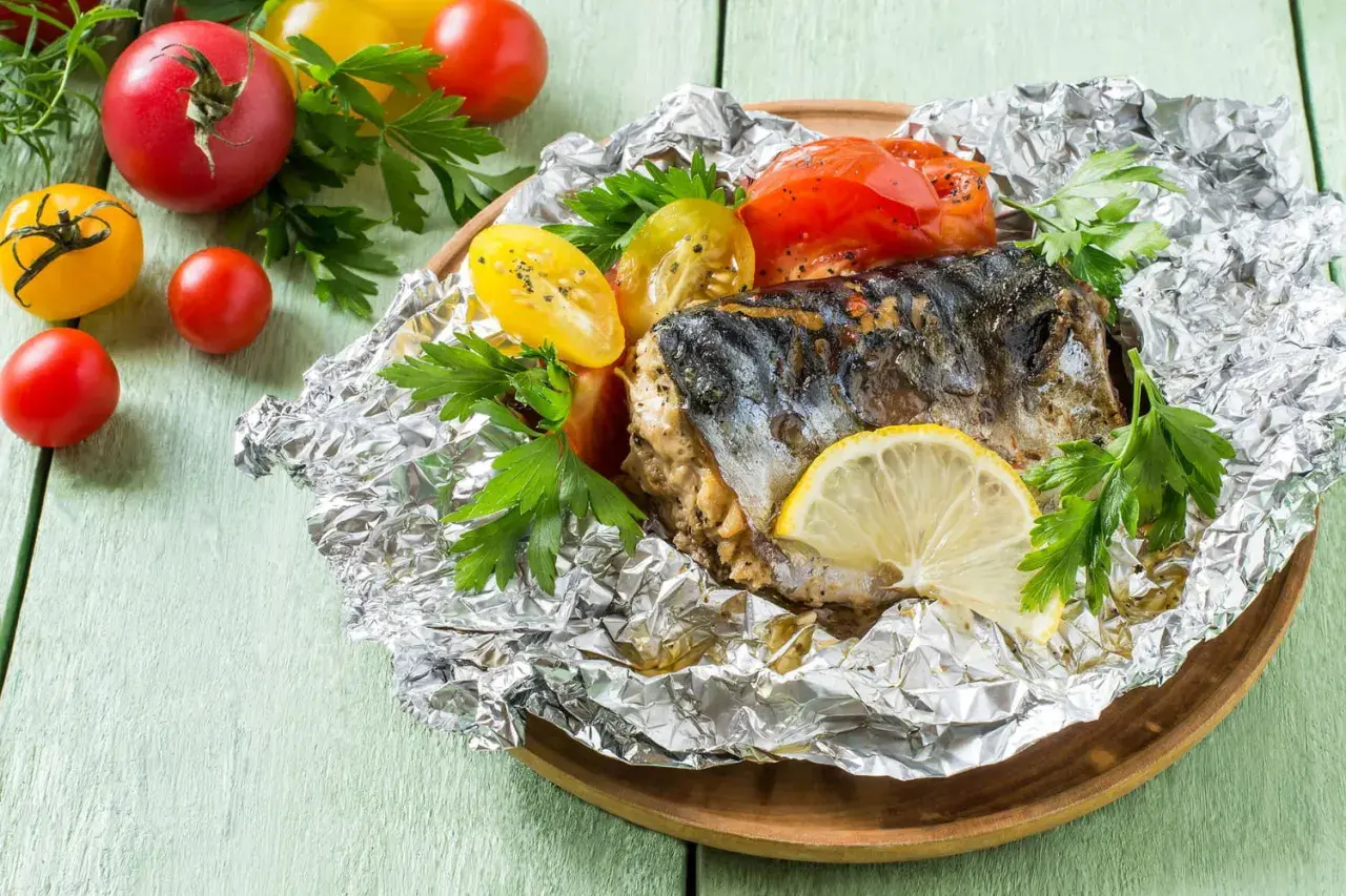Poisson cuit dans l'aluminium, servi avec des tomates et du persil. Un délice simple et savoureux.