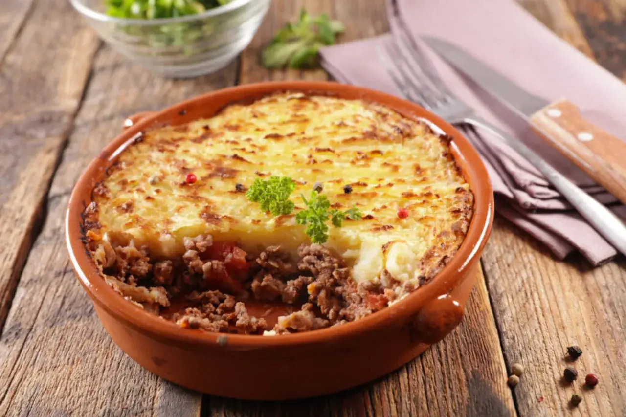 Un plat de hachis parmentier, un classique du repas français, servi dans un plat en terre cuite sur une table en bois.