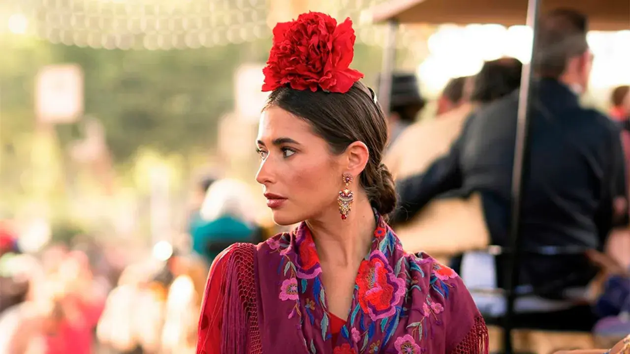 Mujer con flor flamenca en su pelo corto, pendientes llamativos y mantón bordado.