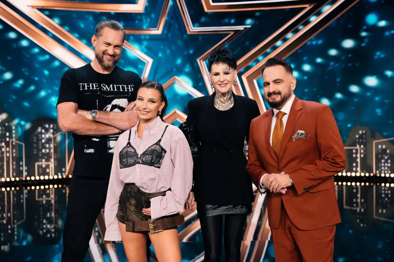 Cztery osoby stoją na scenie z gwiazdą w tle. To jury Mam Talent.