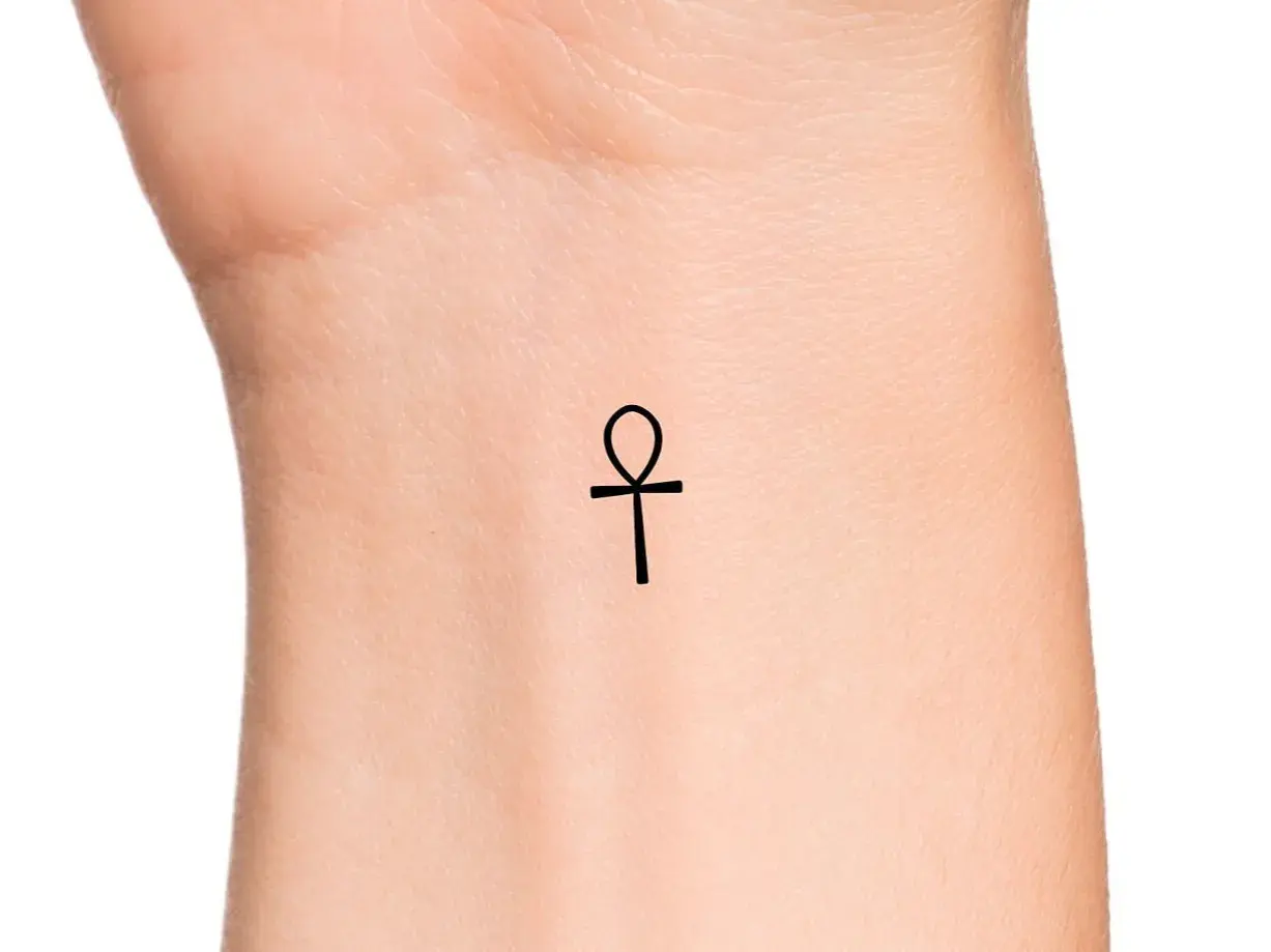 Delikatny ankh tatuaż na nadgarstku, symbol życia i wieczności.