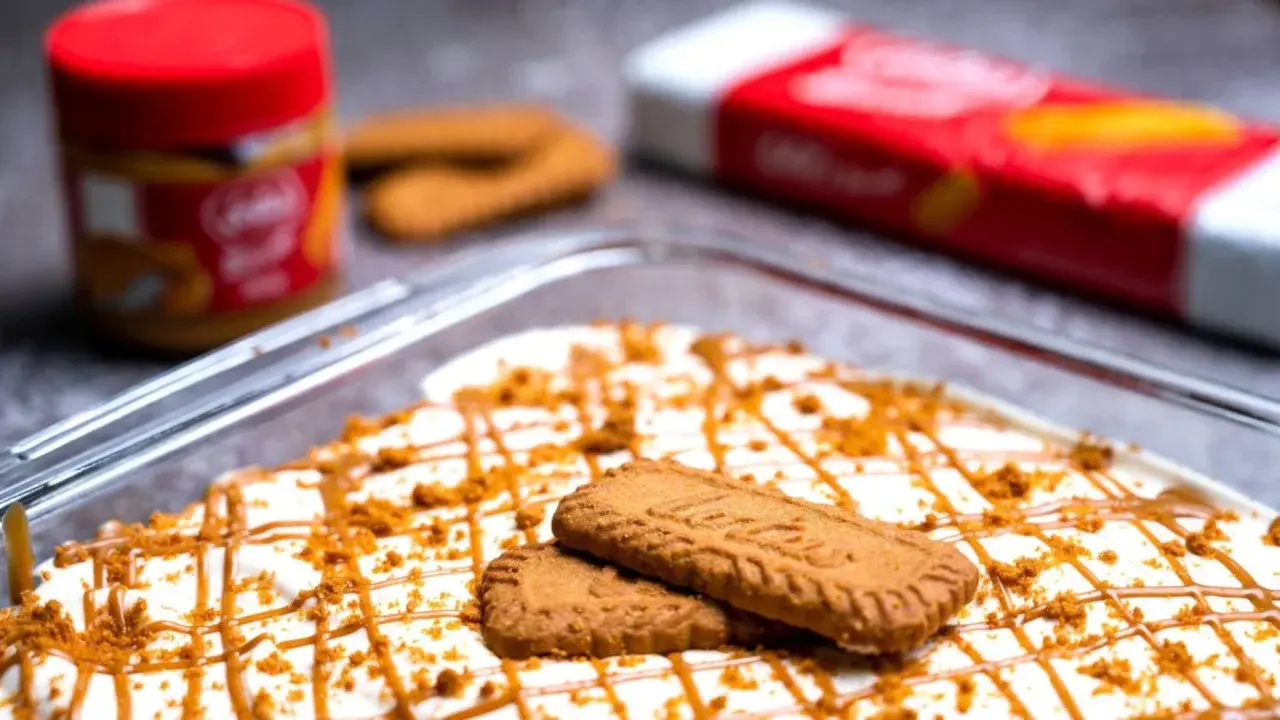 Postre cremoso decorado con galletas y caramelo, con un tarro y paquete de **lotus biscoff ingredients** al fondo.