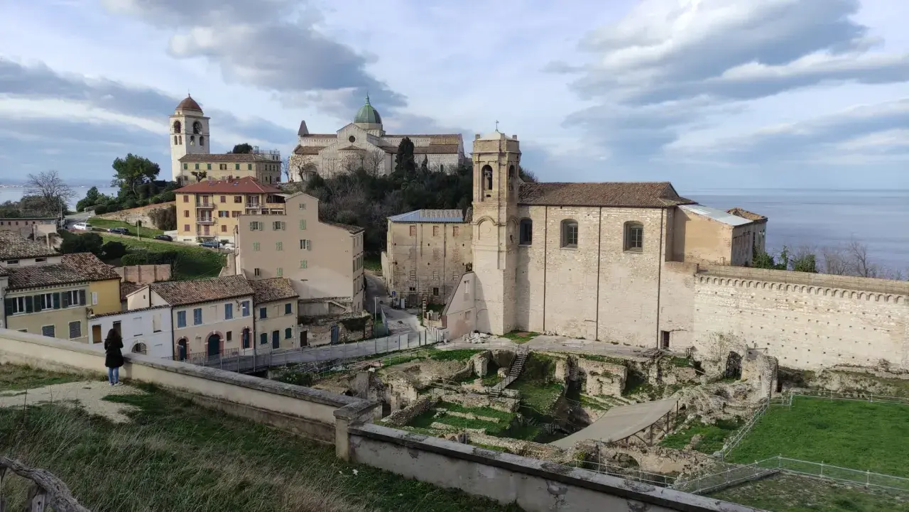 Panoramica del capoluogo Marche con antiche rovine, chiese e il mare all'orizzonte.