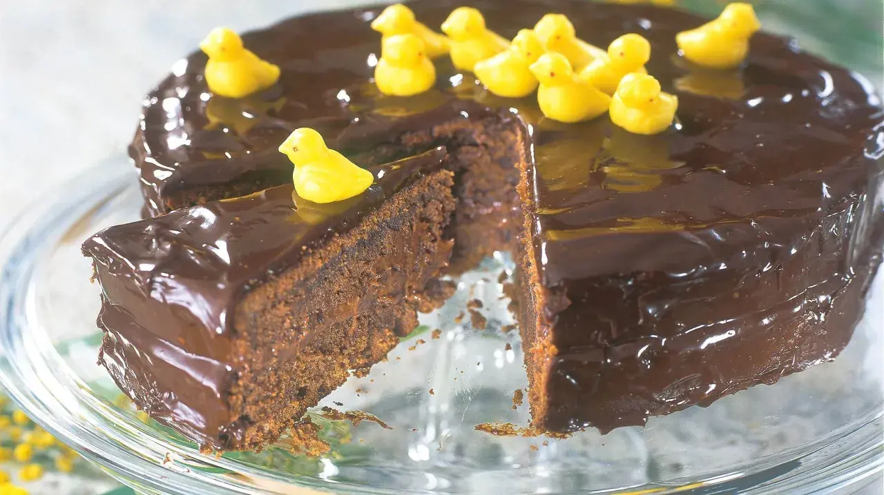 En saftig chokladkaka med blank glasyr, dekorerad med små gula kycklingar. En perfekt påsktårta för alla chokladälskare!