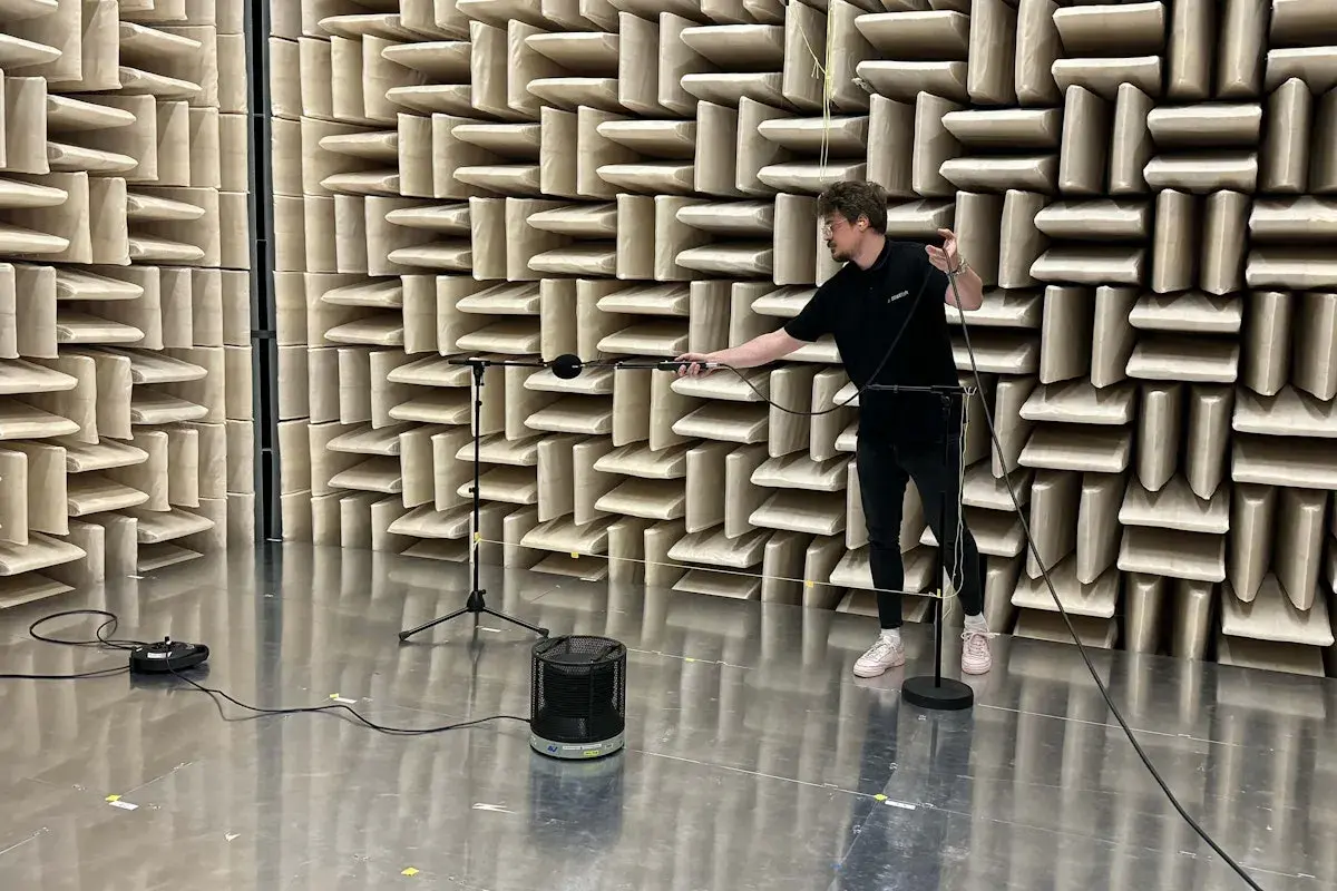 Hombre ajustando micrófonos en cámara anecoica para medir la unidad de potencia acústica de un altavoz.