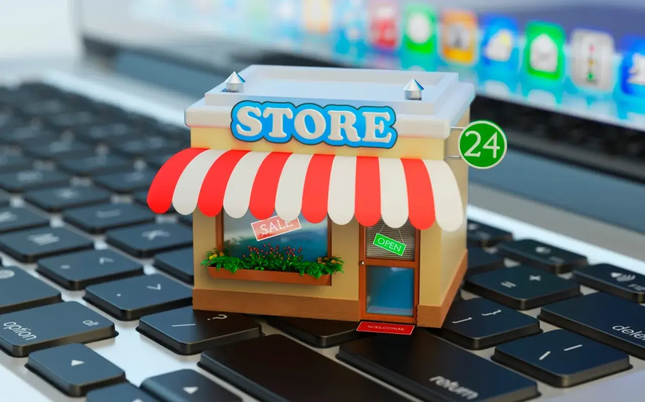 Miniatura de una tienda en línea sobre un teclado de portátil. La tienda tiene un letrero de "STORE", toldo a rayas y un cartel de "OPEN".