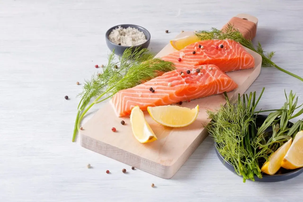 Filetti di salmone fresco, limone, aneto e sale grosso, ingredienti perfetti per una dieta danese sana e gustosa.
