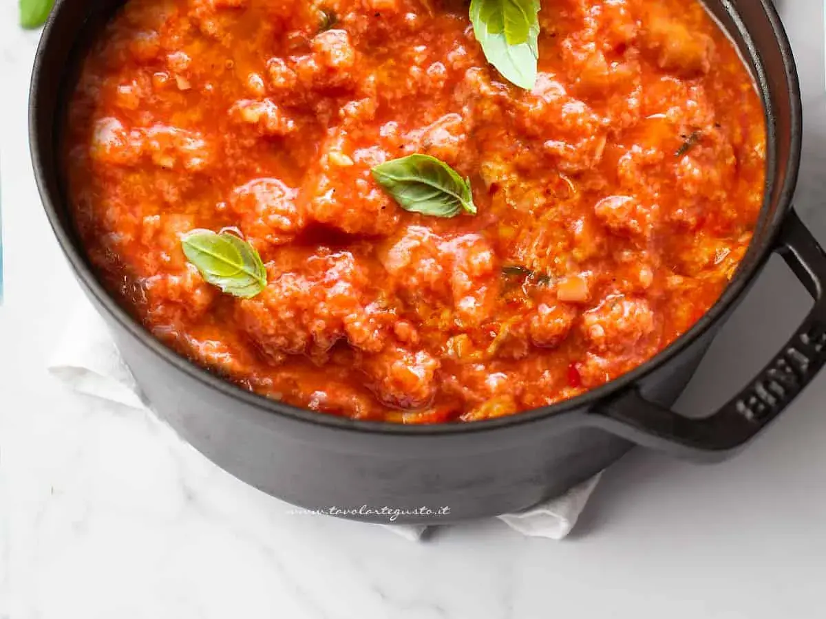 Pappa al pomodoro fumante in una pentola scura, guarnita con foglie di basilico fresco. Un classico comfort food toscano.
