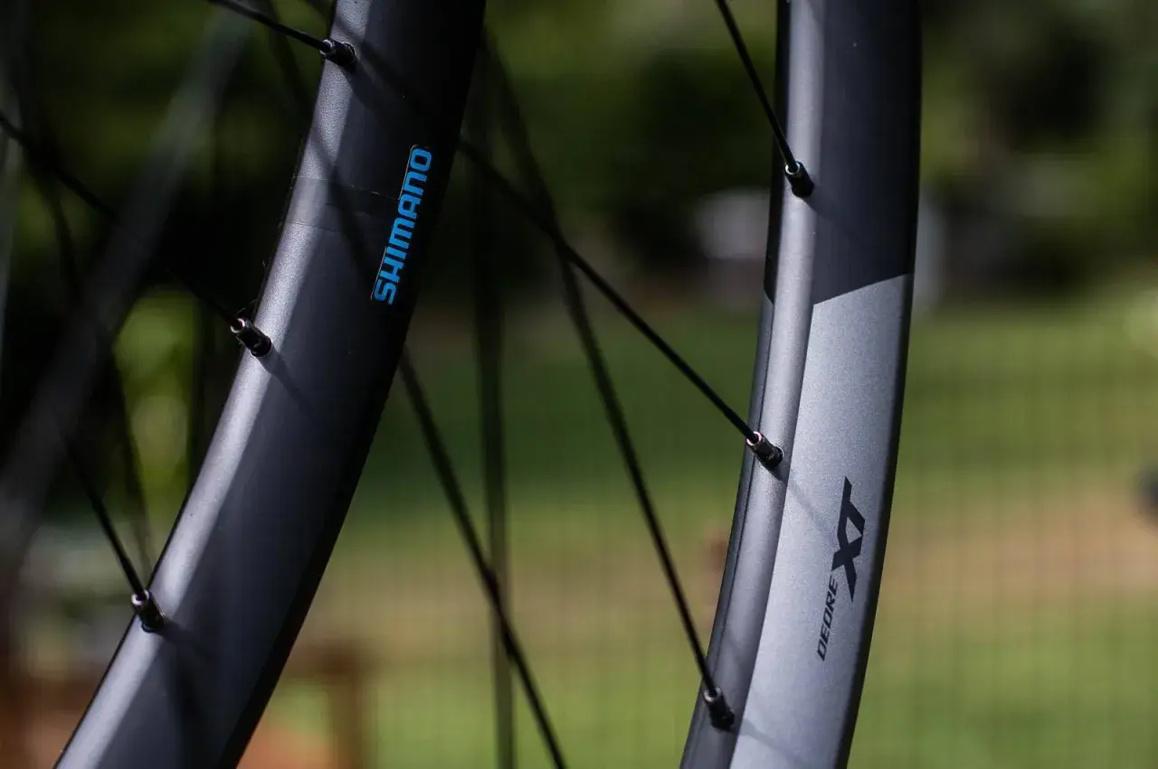 Close-up of two Shimano XT wheelsets, showcasing their durable construction and sleek design, ready for any trail.