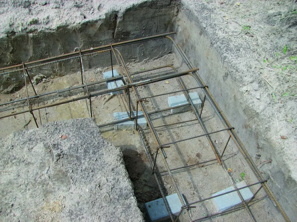 Zbrojenie wieńca w narożu fundamentu, gotowe do zalania betonem. Stalowe pręty tworzą solidną konstrukcję.