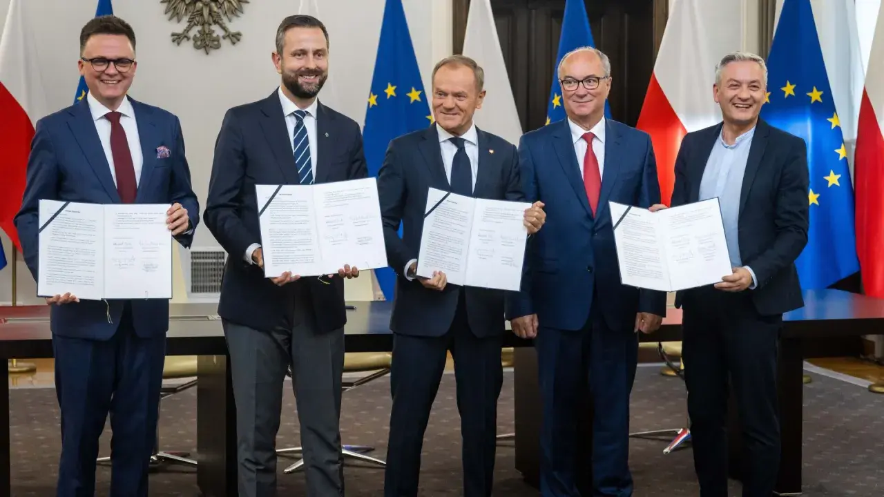 Pięciu polityków prezentuje dokumenty. Ich uśmiechy sugerują sukces, być może związany z tym, ile posłów ma koalicja rządząca.