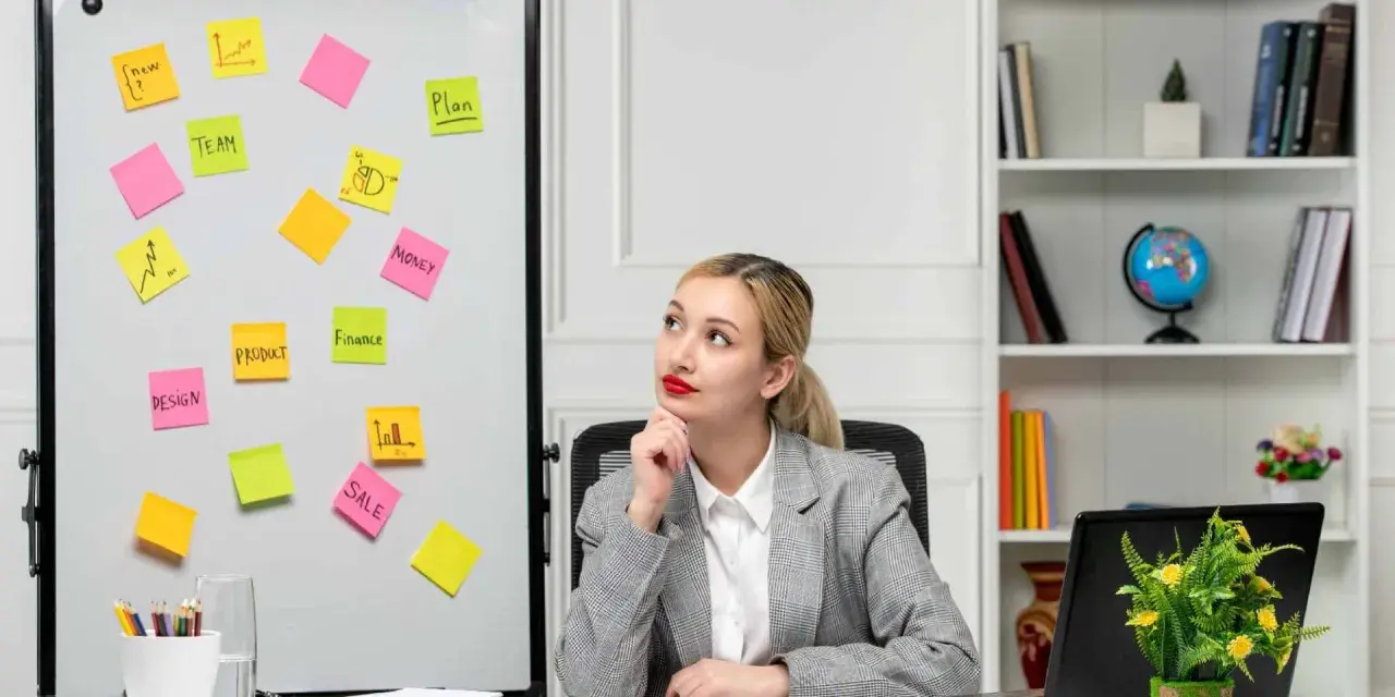 Kobieta zastanawia się nad strategią marketingową. Na tablicy karteczki z hasłami: "TEAM", "PRODUCT", "SALE", "DESIGN", "MONEY", "FINANCE", "PLAN".