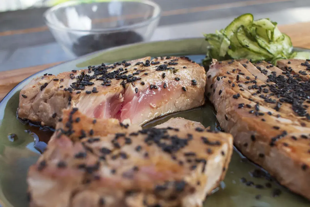 Perfekt gegrillter Thunfisch mit Sesam bestreut, serviert mit Gurkensalat. Ein Genuss für alle Sinne!