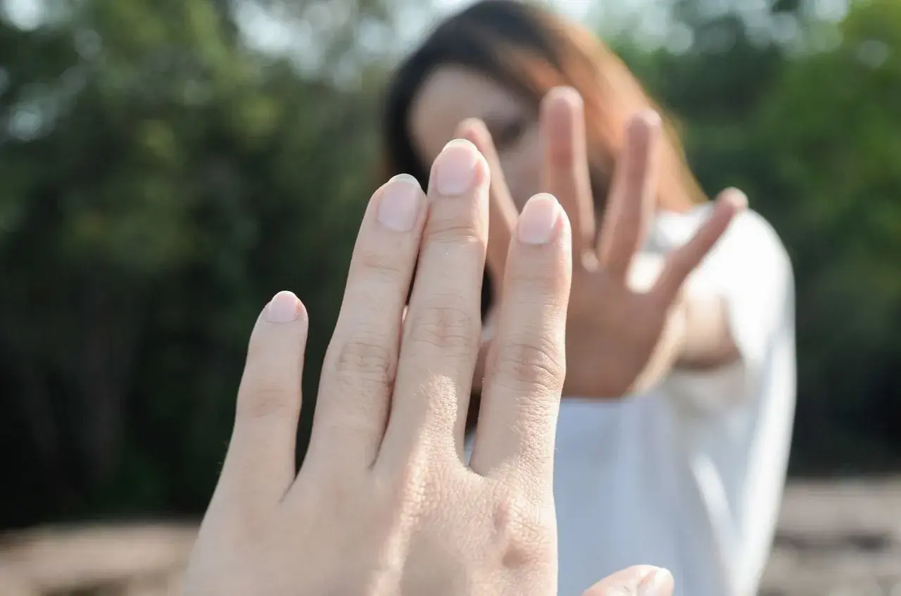 Dłoń w geście "stop" sugeruje trudną rozmowę o tym, jak zerwać z chłopakiem.