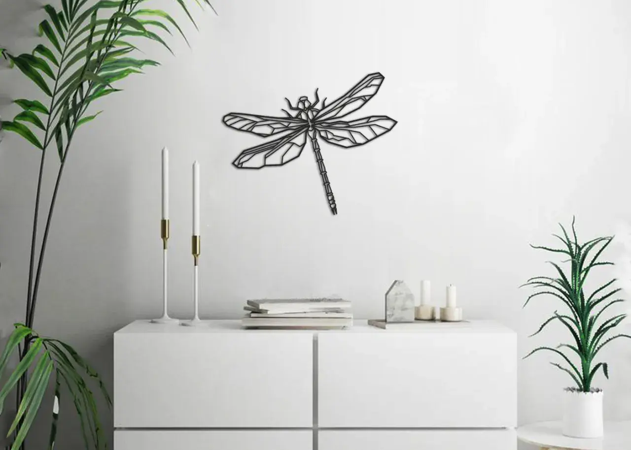 Un moderno cuadro de libélula adorna la pared blanca, sobre un mueble blanco con plantas y velas.