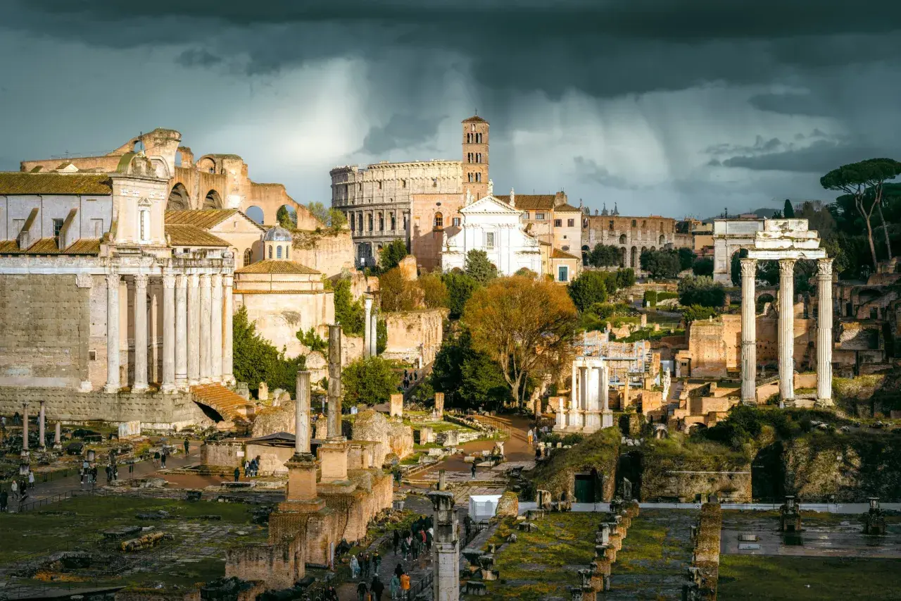 Ruiny Forum Romanum, serce starożytnego Rzymu, pod burzowym niebem. W oddali Koloseum.