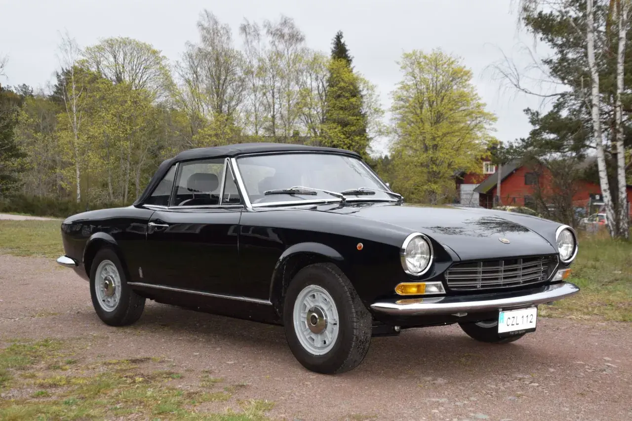 Svart Fiat 124 Spider till salu, en klassisk cabriolet redo för sommarens äventyr.