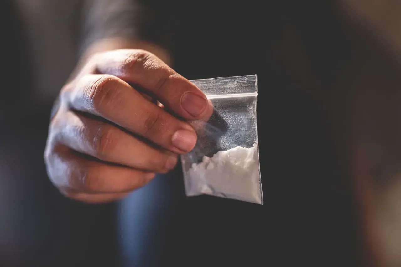 Dłoń trzyma woreczek z białym proszkiem. To może być związane z chemsex, czyli używaniem substancji psychoaktywnych w celu wzmocnienia doznań seksualnych.