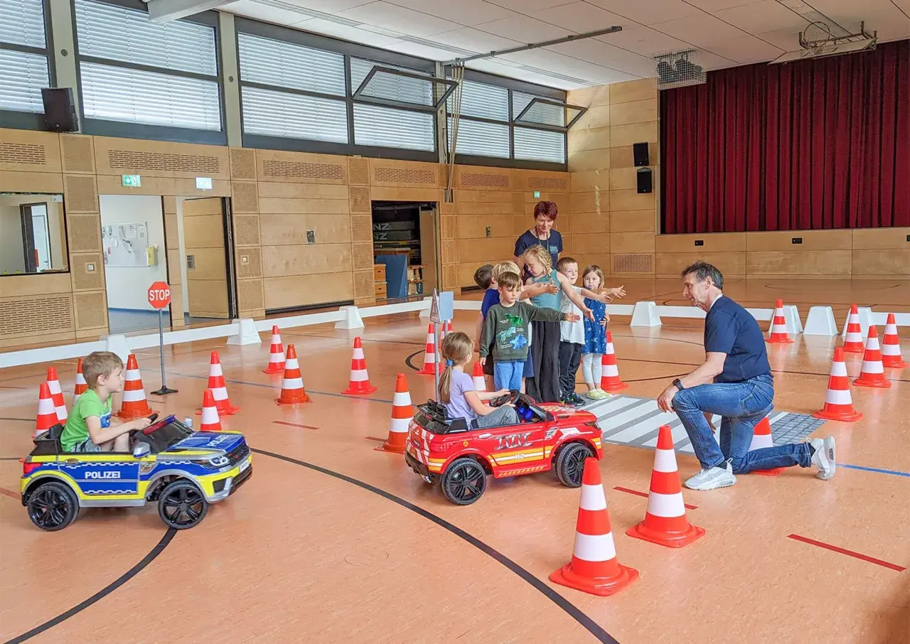 Kinder lernen spielerisch Verkehrsregeln bei der Verkehrserziehung im Kindergarten. Kleine Autos und Pylonen simulieren eine Straße.