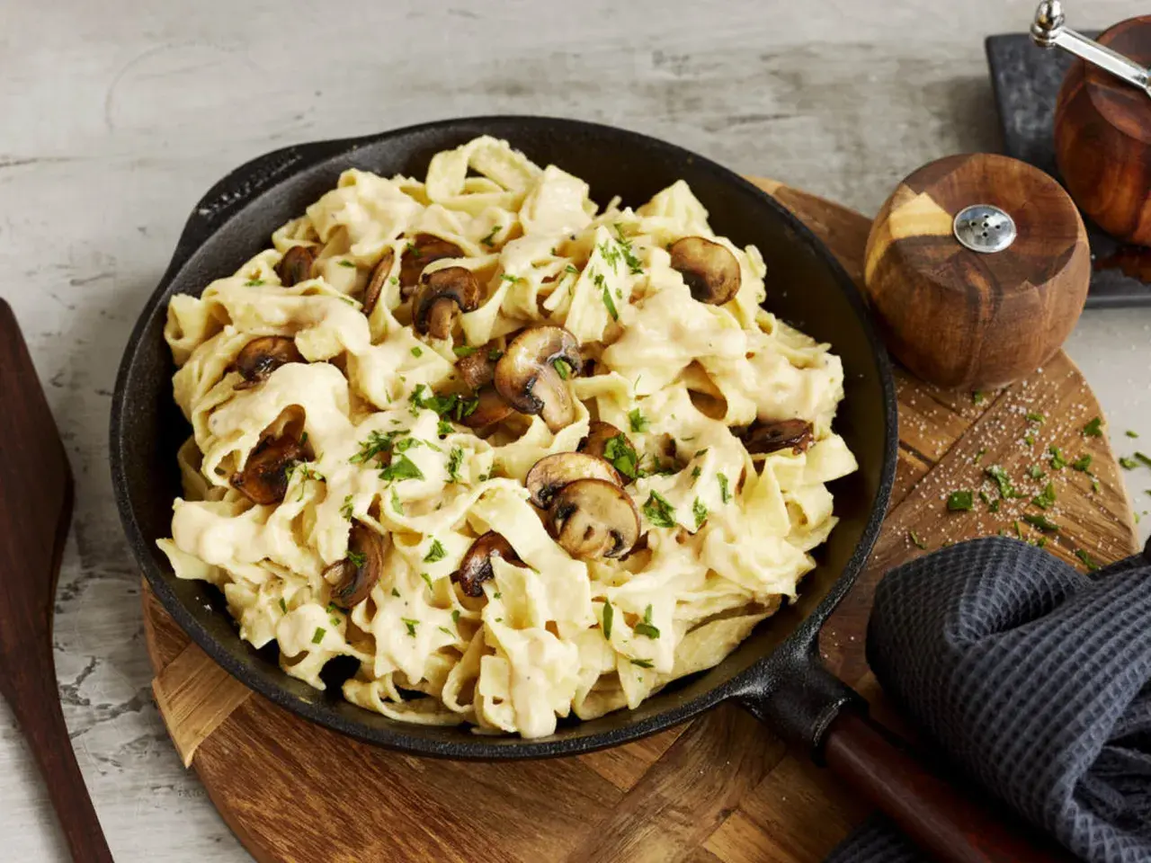 Cremiges Pasta Alfredo mit Pilzen, garniert mit Petersilie, serviert in einer Gusseisenpfanne.