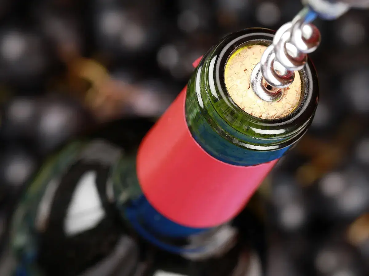 Ein Korkenzieher öffnet eine Flasche Wein, bereit für den Genuss. Ein Glas Wein am Tag hält den Arzt fern.