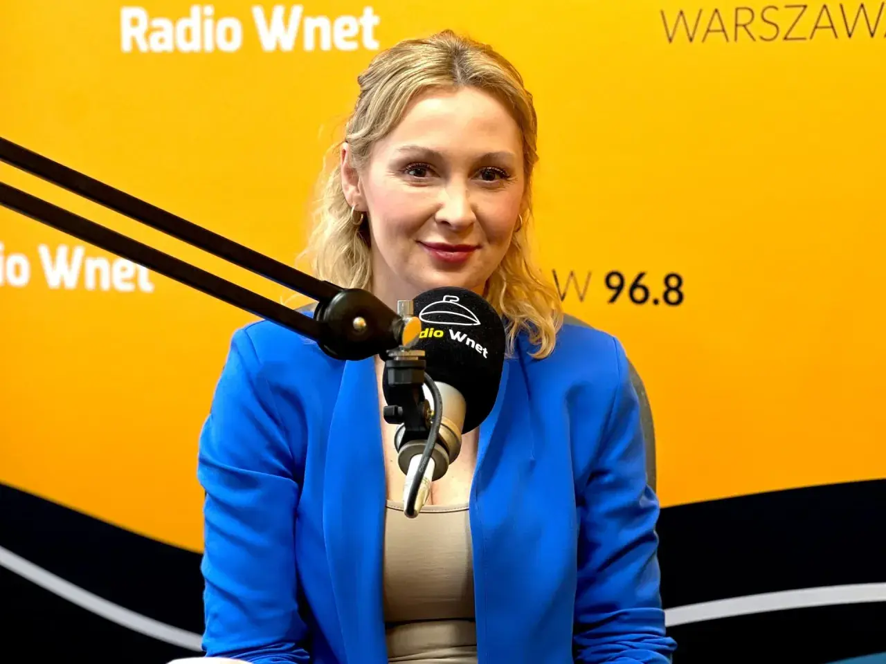 Joanna Miziołek, w wieku około 40 lat, w niebieskiej marynarce, udziela wywiadu w Radiu Wnet.