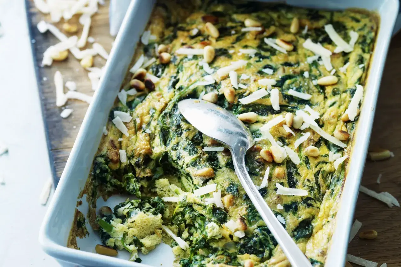 En frittata med spenat och pinjenötter, perfekt för ett snabbt och gott frittata recept. Toppad med riven ost.