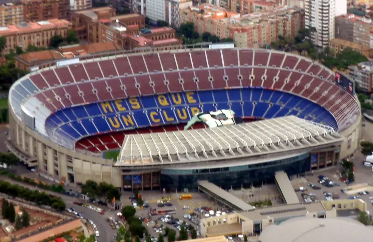 Camp Nou, z imponującą pojemnością, wita kibiców. Na trybunach widnieje napis "Més que un club".