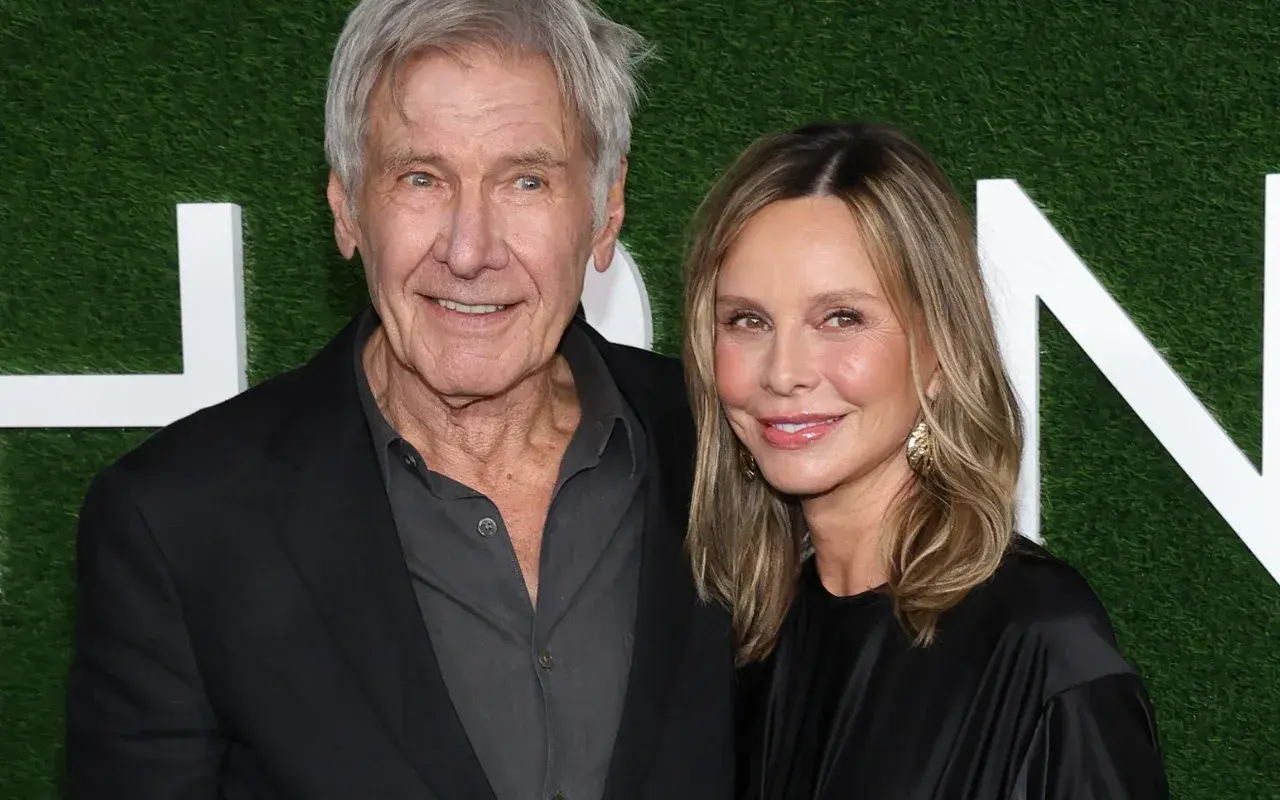 Harrison Ford z żoną Calistą Flockhart na tle zielonej ściany z białymi literami.