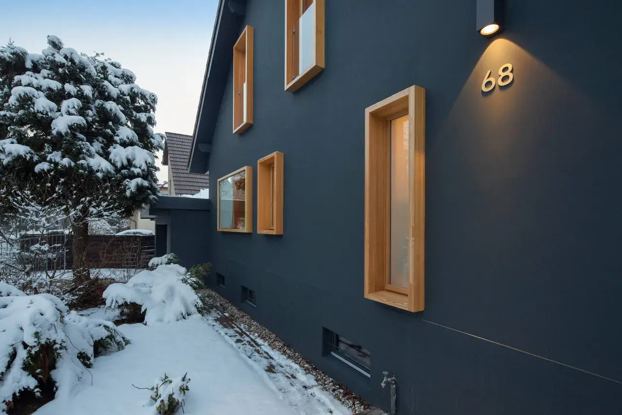 Modernes Haus mit Holzfenstern im Schnee. Ein Architekt hat hier mit klaren Linien und Kontrasten gebaut.