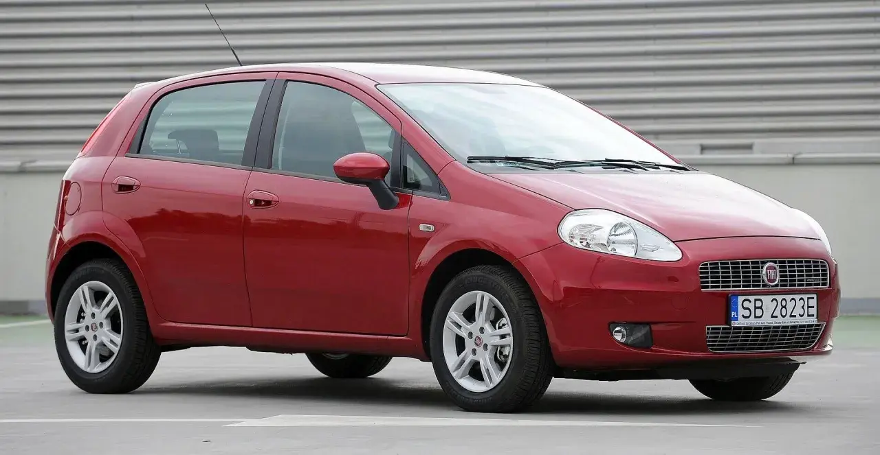 Czerwony Fiat Grande Punto, przód. Wymiana żarówki w reflektorze przednim jest prosta.