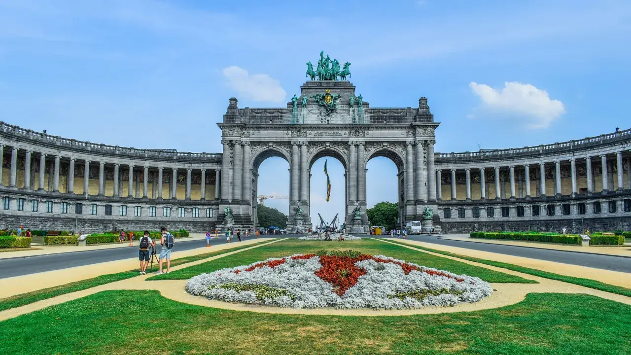 Łuk Triumfalny w Parku Pięćdziesięciolecia, jedna z głównych bruksela atrakcje, z kwiecistą rabatą i turystami.