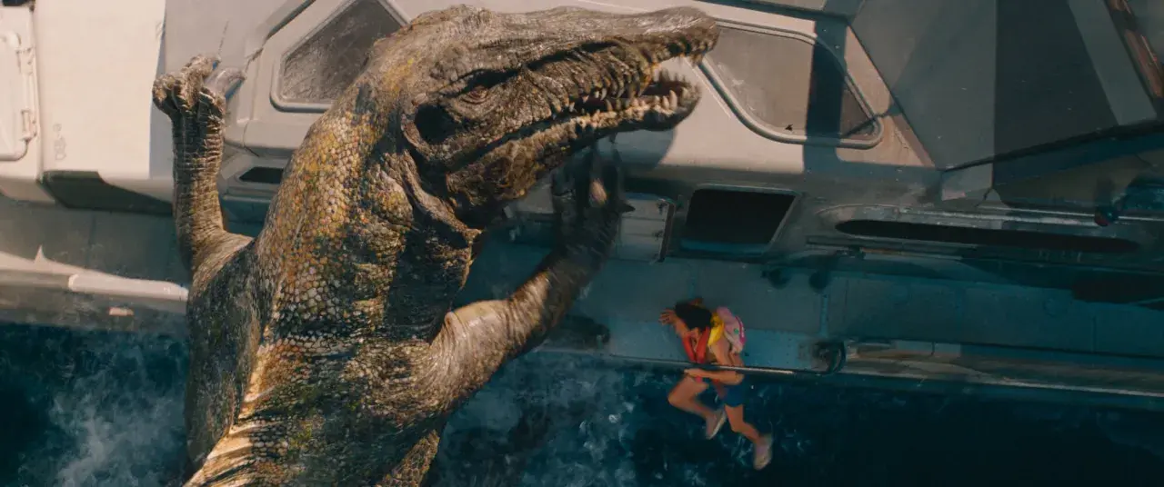 En enorm dinosaurie klättrar upp på en farkost i det nya Jurassic Park, med en liten flicka hängande vid räcket.