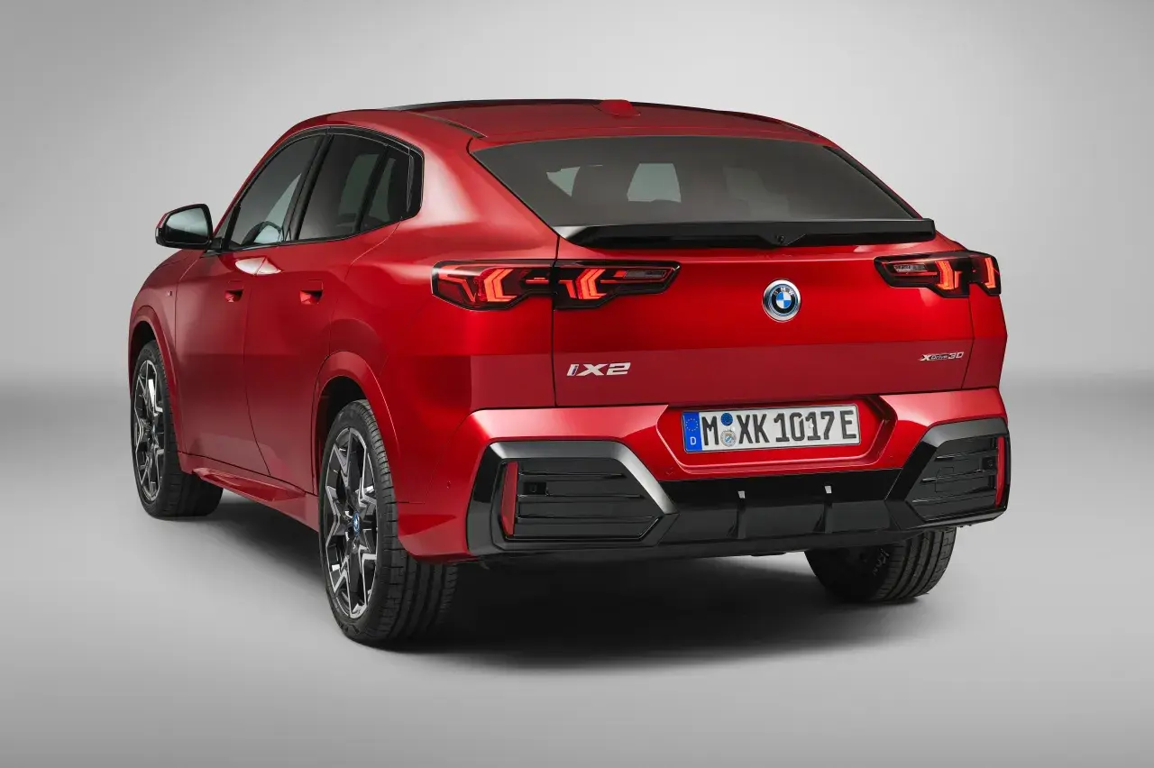 Czerwone BMW iX2 z napisem "XDrive30" na klapie bagażnika, z tyłu widoczne są lampy LED i tablica rejestracyjna.