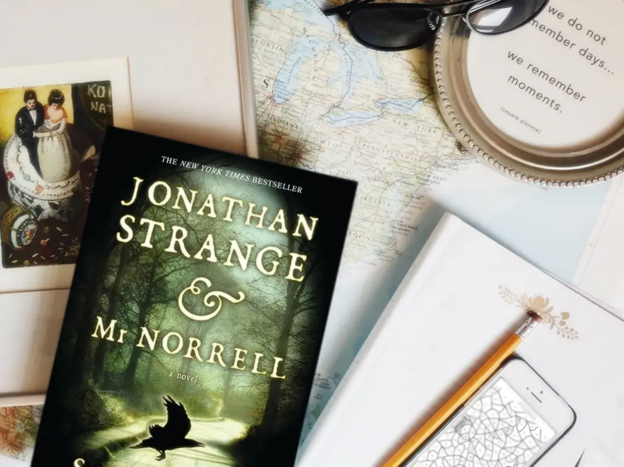 Książka "Jonathan Strange i Pan Norrell" leży obok mapy, telefonu i okularów, gotowa na podróż pełną magii.