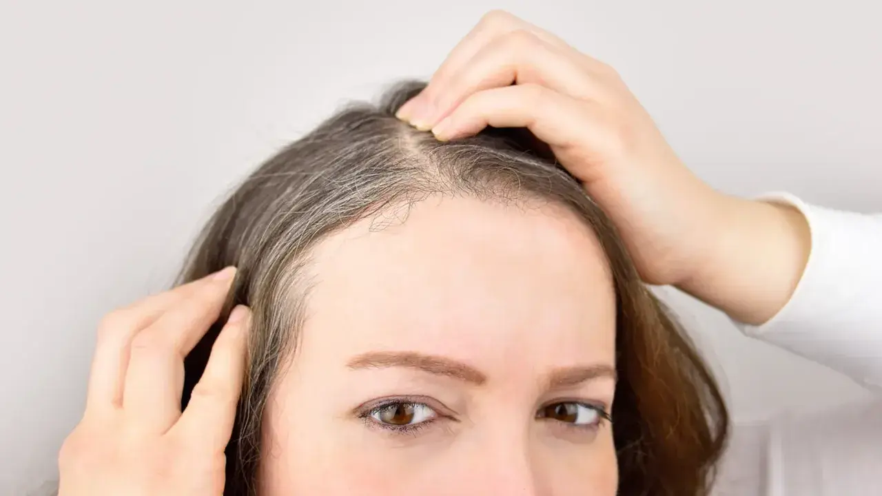 Mujer revisando sus canas, pensando en un baño de color para canas.
