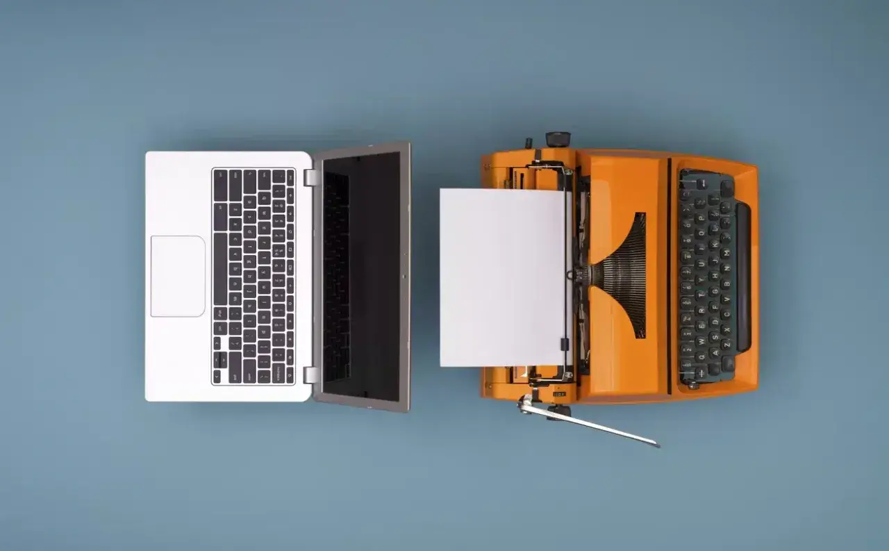 Un portátil y una máquina de escribir naranja con papel, ilustrando como se digitaliza un documento.