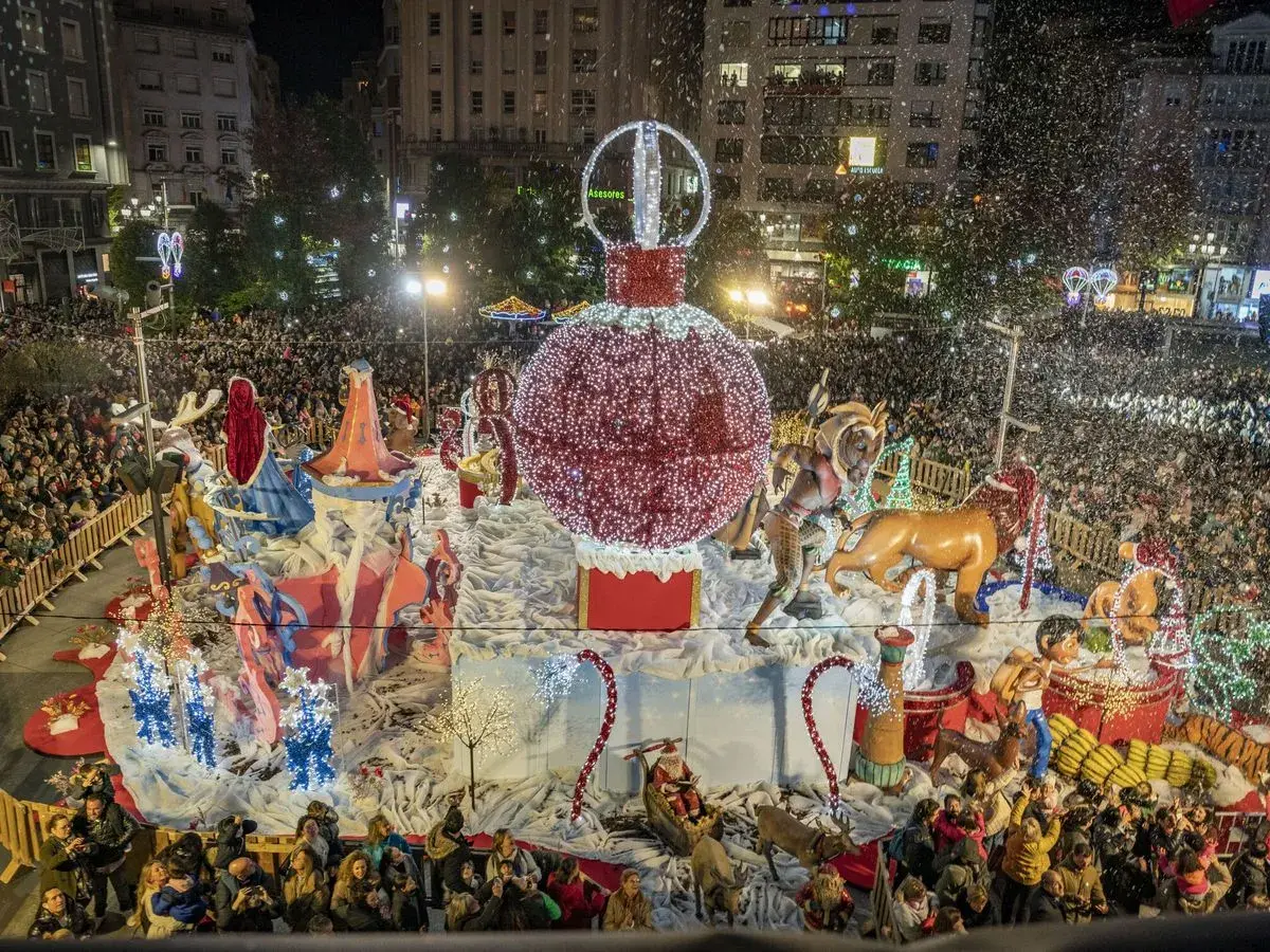 Desfile navideño en Santander con un gran adorno de bola de Navidad y figuras, rodeado de gente y confeti. Encendido luces Santander.