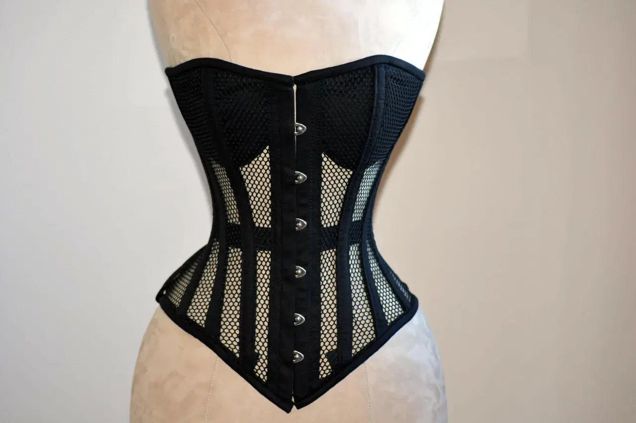 Corsé negro de malla con detalles de tela y broches plateados, diseñado para realzar la figura.