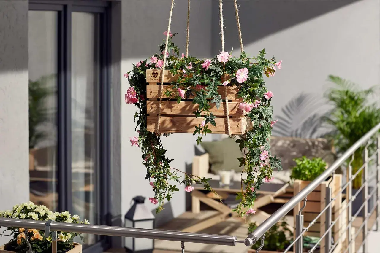 Jolie caisse en bois remplie de fleurs retombantes pour suspension, apportant une touche de couleur et de verdure à un balcon.