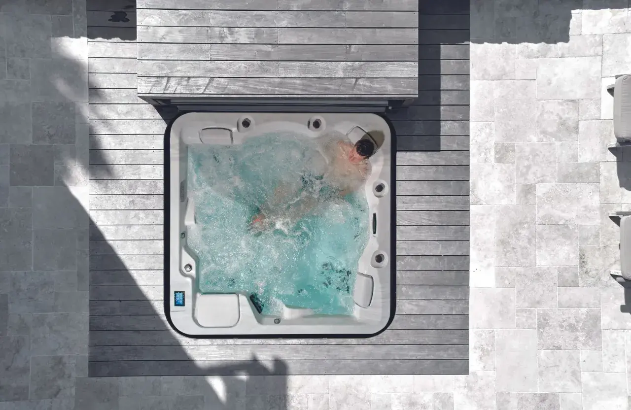 Un homme profite d'un traitement spa relaxant dans un jacuzzi bouillonnant, entouré de bois et de pierre.
