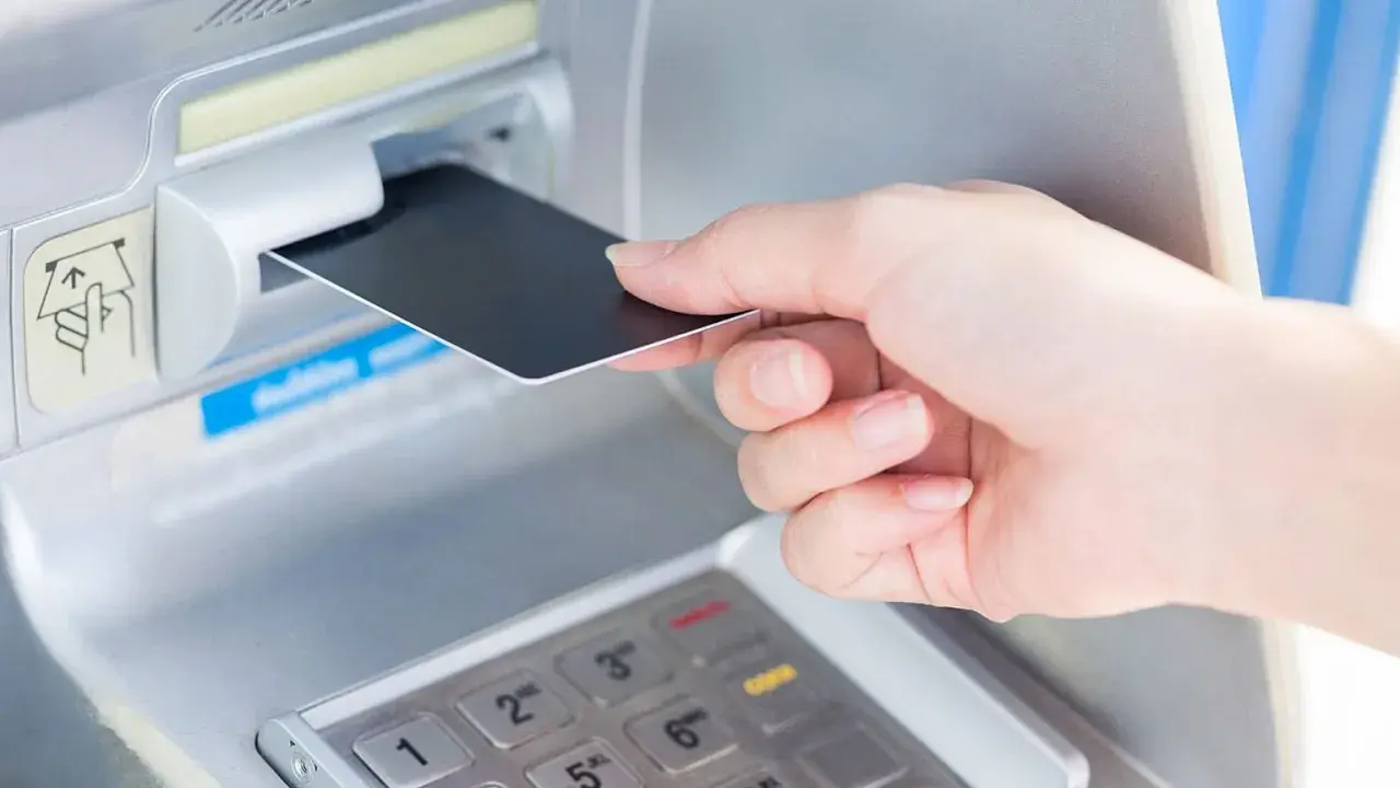 Wkładanie karty do bankomatu. Planując podróż, warto sprawdzić, czy w Norwegii można płacić euro.