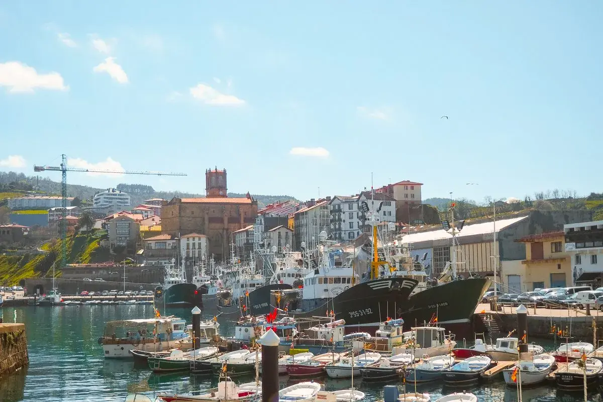 Puerto de Getaria, cerca de San Sebastián, con barcos de pesca amarrados y edificios pintorescos en la colina.