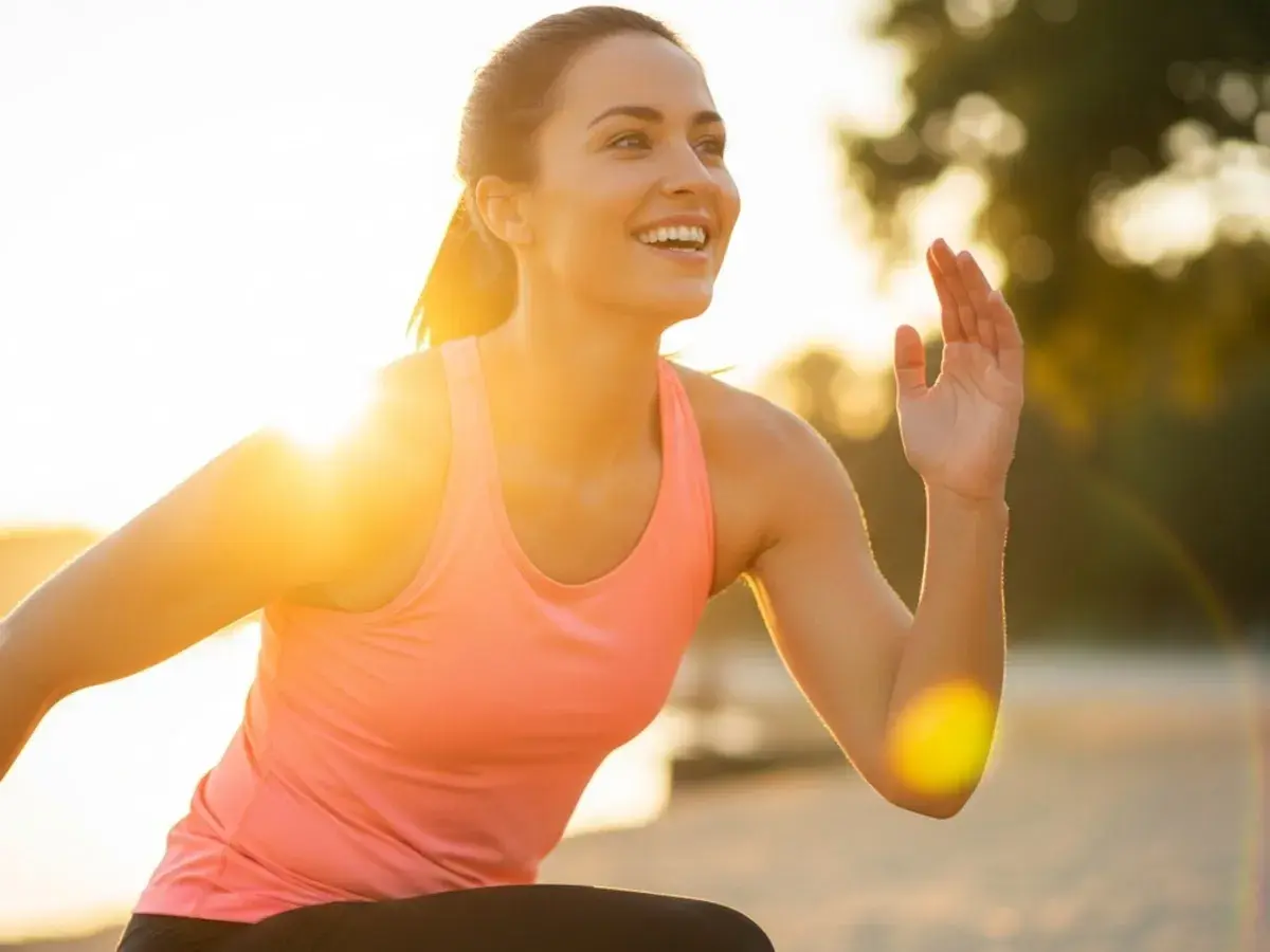 Mujer sonriente corriendo al atardecer, un secreto para como mantenerse joven es la actividad física y disfrutar del sol.